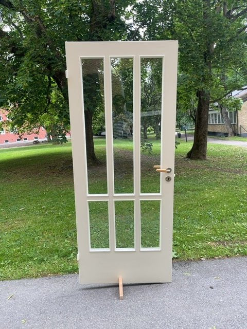 Glasdörr från 50-talet i vitmålad massiv furu. Kantlister kring glas i vitmålad ek. Färgskav kan förekomma.